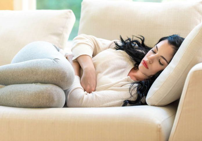 Young,Woman,Suffering,From,Stomach,Pain,In,A,Bright,Interior