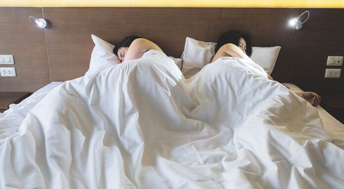 Asian couple lying on bed boring each other